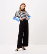 Pantalón wide leg negro de crepé, de corte recto y tiro alto, con bolsillos discretos y pasadores en la cintura. Incluye un cinturón fino de cadena metálica dorada.