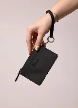 Billetera negra tipo tarjetero de material sintético, con cierre superior, bolsillo frontal y correa de muñeca con argolla metálica.