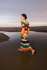 Vestido largo tejido a crochet con diseño calado y rayas horizontales de colores: blanco, verde, rojo, naranja, amarillo, negro y naranja.