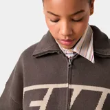 Campera de tejido de punto marrón con cierre frontal y cuello tipo polo. Presenta un diseño de bloques de color con franjas beige en el pecho y los brazos, y la palabra "EME" estampada en grande en el frente.