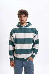 Canguro con capucha de corte holgado, con diseño de rayas horizontales anchas en color verde y beige. Cuenta con bolsillo frontal tipo canguro y puños y ruedo acanalados.