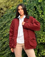 Campera tipo encerada de color azul oscuro, con cuello alto, cierre frontal de botones metálicos dorados, bolsillos frontales con solapa y bolsillos laterales en el pecho.