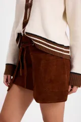 Minifalda de cuero con efecto desgastado, de silueta recta y diseño de capas frontales superpuestas. Incluye un lazo ajustable en la cintura que pasa por ojalillos metálicos y bolsillos laterales integrados.