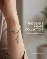 Pulsera tipo rosario de acero con baño de plata, compuesta por pequeñas cuentas esféricas, un dije en forma de corazón con la figura de la virgen niña en su interior y un colgante con una cruz.
