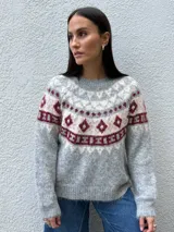Sweater de punto con diseño nórdico en el canesú, de cuello redondo y manga larga. Presenta una combinación de colores gris, crudo y bordó con textura suave.