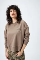 Buzo color marrón de corte relajado confeccionado en tejido de algodón con interior suave al tacto. Presenta detalle de estrella con tachas en la espalda y bordado delantero con la frase Dreamer – Born to rock.