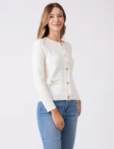 Cardigan de punto color fucsia, con escote a la base, cierre frontal con botones metálicos dorados y terminaciones desflecadas. Presenta bolsillos simulados en la parte delantera y mangas largas.