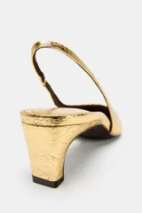Zapatos tipo kitten heel destalonados, de color dorado con acabado metalizado texturizado, tacón bajo ancho y punta fina.