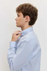 Camisa celeste de manga larga con cierre frontal de botones y cuello clásico.