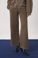 Pantalón de jogging de corte recto y holgado, confeccionado en tejido de punto color marrón con efecto lavado. Presenta cintura elástica y aberturas laterales en el ruedo.