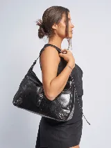 Cartera negra de cuero sintético con asa al hombro regulable y cierre con broche imantado.