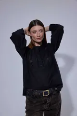 Camisa blanca de algodón con pechera decorada con alforzas y puntillas. Presenta cierre frontal con botones, mangas tres cuartos con frunces y detalles de puntilla, y un diseño de corte holgado con ruedo redondeado.