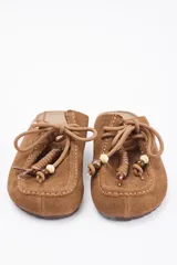 Zueco de cuero vacuno color marrón, con diseño de puntera reforzada y cordones decorativos con cuentas de madera en el empeine.