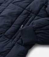Campera puffer de hombre reversible, con diseño acolchado, cuello alto, capucha y cierre frontal.
