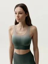 Top deportivo sin mangas de diseño degradado que transiciona de beige en los hombros y pecho a verde oscuro en la parte inferior, con escote redondo y sostén integrado.