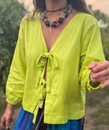 Blusa color verde lima con escote en V, mangas largas abullonadas con puños elásticos y cierre frontal con lazos.