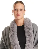 Ruana tejida con diseño color block en tonos grises y beige, con cuello de piel sintética y terminación en flecos.