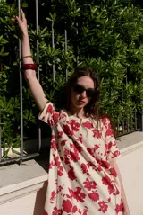 Vestido midi de manga corta, con diseño holgado, cuello redondo y estampado abstracto con detalles florales en tonos marrones y violetas.