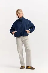 Campera de jean azul de corte amplio y largo a la cintura, con cuello alto, cierre frontal con botones a presión y bolsillos ojal delanteros.