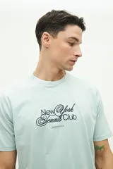 Remera clásica de manga corta, color verde menta, con estampado frontal que dice "New York Tennis Club" y "Brooksfield" en azul marino.