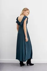 Vestido largo negro de escote redondo con volados decorativos que recorren el frente y la espalda. Presenta un cordón de ajuste en la cintura con terminaciones metálicas y espalda baja.