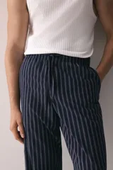 Pantalón de popelina de algodón azul marino con finas rayas verticales blancas. Presenta cintura elástica con cordón ajustable y bolsillos laterales.