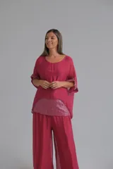 Blusa de seda color bordó con diseño holgado, cuello redondo y mangas cortas tipo kimono. Presenta un panel frontal inferior y detalles en las mangas con lentejuelas al tono.