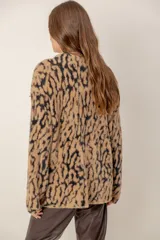 Cárdigan de punto con textura suave y estampado animal print en tonos marrones y beige. Presenta escote en V, cierre frontal con botones y mangas largas holgadas.