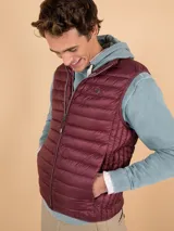 Chaleco acolchado de hombre color gris, con diseño matelasseado horizontal, cuello alto y cierre frontal completo. Presenta un calce ajustado y detalle de logo circular bordado en el pecho.