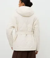 Campera acolchada de microfibra color crema, con diseño capitoneado, capucha integrada, cierre frontal oculto y cinturón ajustable del mismo tejido para entallar la silueta.