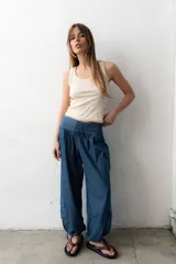 Pantalón estilo babucha color azul, de corte ancho con pretina ancha fruncida y cordones cruzados al frente. Cuenta con bolsillos cargo laterales y botamangas ajustables.