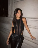 Body negro sin mangas con paneles de malla transparente en el frente y aberturas laterales pronunciadas.