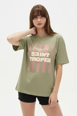Remera de algodón color beige con estampado frontal de un corazón rosado que contiene un moño. Tiene cuello redondo y mangas cortas.