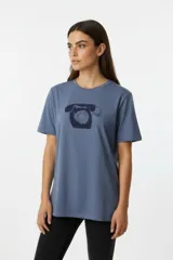 Remera de algodón de corte holgado, color azul grisáceo, con cuello redondo y estampado frontal de un teléfono antiguo en color azul oscuro.