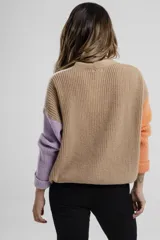 Cárdigan de punto color crema con mangas largas y terminaciones en color naranja y lila. Posee cuello en V y cierre frontal con botones color madera.