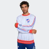 Buzo de cuello redondo color azul, con detalles en rojo y blanco en cuello, puños y ruedo. Presenta el escudo del Club Nacional de Football en el pecho y bandas laterales con diseño deportivo en las mangas.