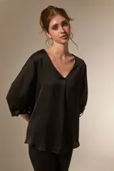 Blusa de satén color bordó con cuello en V y mangas tres cuartos. Presenta un diseño holgado con un pliegue central en el frente.