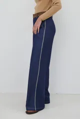 Pantalon de corte recto y pierna ancha, confeccionado en tela tipo denim color azul oscuro, con costuras a contratono y detalle de abertura lateral en el ruedo.