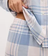 Pijama de dos piezas estilo americano confeccionado en franela. La blusa cuenta con cuello solapa, manga larga, cierre frontal con botones y un bolsillo en el pecho. El pantalón posee cintura elástica. Ambas prendas presentan un estampado de cuadros en tonos azul y blanco.
