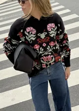 Buzo tejido de algodón negro con diseño jacquard de flores multicolor, cuello en V y mangas largas.