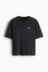 Remera de algodón de punto pesado en color negro con efecto lavado, cuello redondo acanalado, hombros caídos y pequeño estampado tipográfico en el pecho.