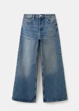 Jeans de denim azul de corte wide leg, con aplicación de pequeños tachas o strass plateados en toda la prenda.