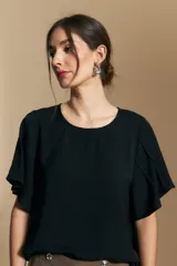 Top de color azul, con escote redondo a la base y mangas cortas amplias con caída fluida. Presenta una silueta relajada y un diseño minimalista.