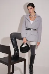 Saco corto estilo blazer gris claro, de tejido afelpado, con cuello solapa y bolsillos delanteros.