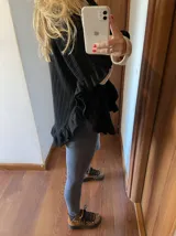 Sweater color beige de tejido de punto con cuello alto, mangas largas y corte asimétrico con volados en el ruedo.