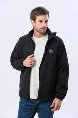 Campera repelente al agua y cortaviento de color negro, con capucha desmontable, cierre frontal y parche circular en el pecho.