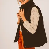 Chaleco negro con cierre frontal de cremallera y cuello alto.