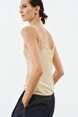 Top lencero de satén color beige con escote redondo y tirantes anchos, con aplicación de encaje a tono en el escote y los tirantes.