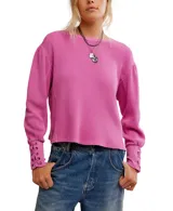 Buzo de algodón color fucsia, de calce relajado con escote a la base, hombros caídos y mangas amplias con detalle de ojalillos y cordones cruzados en los puños.