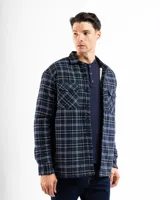 Sobrecamisa de franela a cuadros en tonos azul y negro, con forro interior de corderito, cierre frontal de botones, cuello clásico y dos bolsillos frontales con solapa.